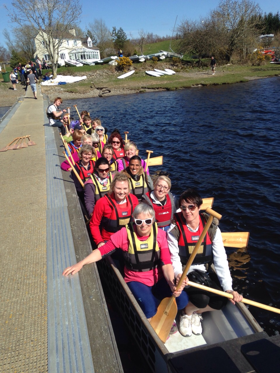 The team in a big boat. They are holding paddles